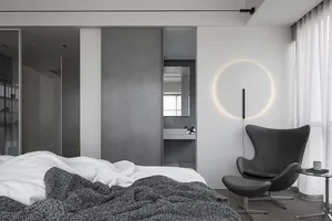 A minimalist bedroom featuring a concrete wall and a circular light fixture.