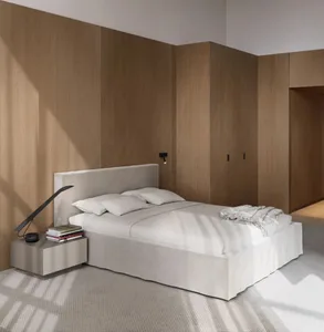 A minimalist bedroom with a white bed sheet, a headboard, and a nightstand with a lamp and books.