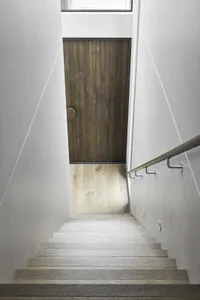 A minimalist staircase with wooden steps and white walls.