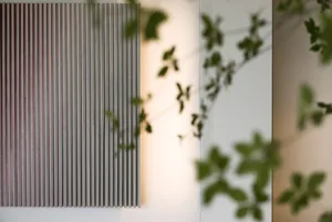 A minimalist modern indoor wall paneling setup featuring natural light and plant shadows