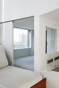 Minimalist bedroom with white bedding and a view of the city.