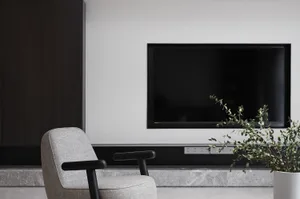 A modern minimalist living room with a marble accent wall and furniture.
