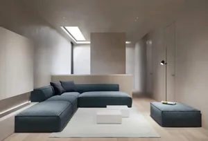 A modern living room with a blue sectional sofa, white coffee tables, and white rug.