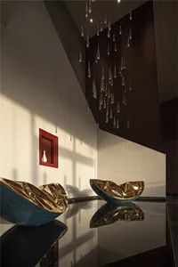 A modern lobby featuring metallic glass sculptures and a droplet-shaped hanging light fixture.