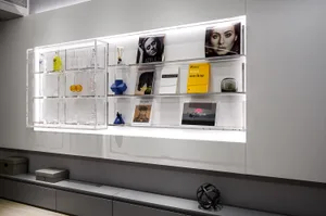 Modern minimalist shelf display featuring clear glass shelving with books, glassware, and decorative items.