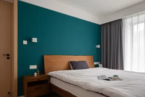 A minimalist bedroom with a wooden bedframe, teal accent wall, and a window with sheer curtains.