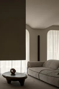 A minimalist living room featuring a fabric coffee table with a unique wooden sculpture on top, and a comfortable sofa.