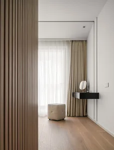 Modern bedroom featuring wooden flooring, a hanging desk with a round mirror, and curtains.