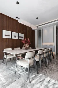 Modern dining room featuring a marble table, white leather chairs, and metal legs.