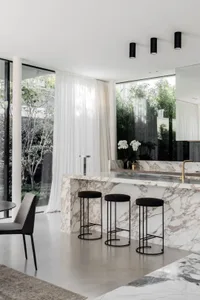 A modern interior space featuring a marble countertop and stools with a minimalist decor.