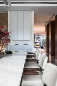 Modern kitchen interior with white marble countertops and chairs.