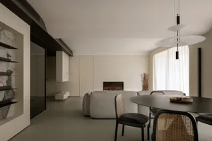 A modern living and dining room featuring neutral-toned furniture and a cozy fireplace.