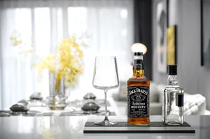 Modern living room featuring a glass counter with a glass bottle of Jack Daniel's whiskey and an empty wine glass.