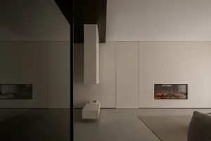 A minimalist living room with concrete walls and an electric fireplace.