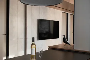 A modern minimalist living room with tiled walls and a flat-screen TV.