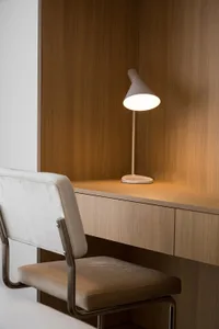 A minimalist office desk space featuring a wooden chair and table lamp.