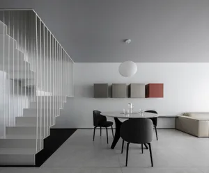 A minimalist modern dining room featuring sleek, black chairs and a white marble table with a black base.
