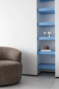 A modern living room featuring blue floating shelves with various decorative items including a red camera and two ceramic fig
