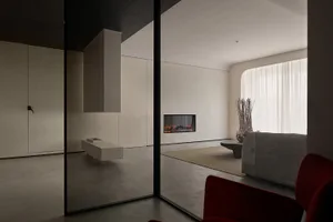 A modern living room featuring concrete walls and glass elements.