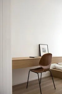 A minimalist home office with a wooden desk and chair, featuring a simple design and clean lines.
