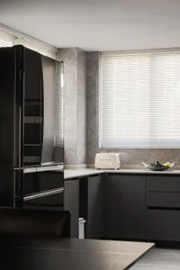 Modern minimalist kitchen with stone backsplash, glass cabinets, and stainless steel appliances.