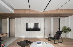 A modern living room with marble walls, light-colored wood flooring, and a sleek black armchair.