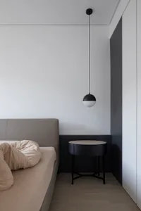 Minimalist bedroom with a bed, a bedside table, and a matte black pendant light hanging from the ceiling.