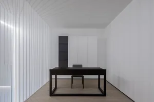A minimalist office space with a black metal desk and black chair.