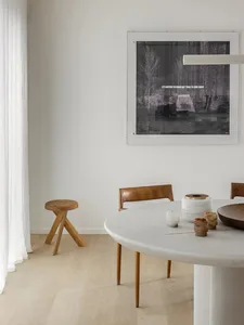 Modern dining room featuring a round marble table and wooden chairs.