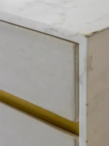 A sleek, modern side table made of white marble with gold accents.