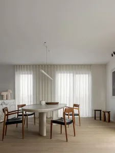 A modern dining room with neutral colors, featuring a minimalist table, wooden chairs, and large windows with sheer curtains.
