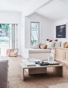A minimalist living room with white walls, a wooden cabinet, and a concrete coffee table with books and a tray.