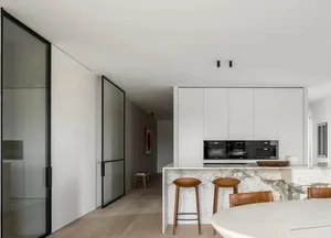 A modern kitchen featuring a marble island counter and white cabinets.