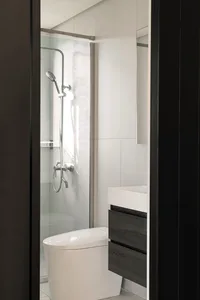 Modern minimalist bathroom with concrete walls, glass shower enclosure, and white fixtures.