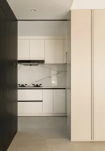 A modern minimalist kitchen with a white marble countertop and white cabinets.