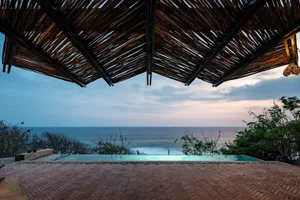 A wooden roof with a view of the ocean and tropical surroundings.