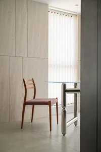 A minimalist interior design featuring wooden furniture, glass table, and metal accents.