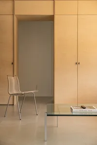 Modern interior space featuring minimalist, sleek wood cabinets and a glass coffee table with books and a remote.