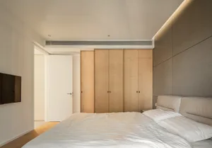 Modern minimalist bedroom featuring wooden cabinets and a white bed.