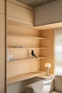 A modern residential shelving space featuring wooden shelves with decorative objects and a sleek desk lamp.