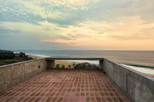 Concrete terrace overlooking the sea with red brick tiles on the floor.