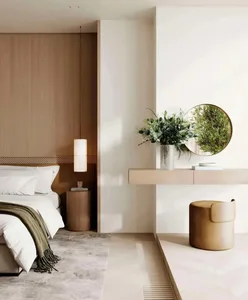 A minimalist bedroom featuring a wooden headboard and a white bed with green throw blanket.