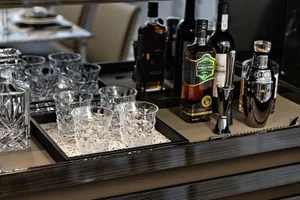 A sleek, modern bar counter featuring polished glass and ceramic materials, with various bottles and glasses neatly arranged.