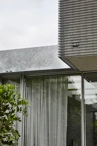 Modern exterior of a house with stone cladding and large glass windows.