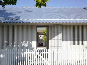 Modern house exterior with metal cladding and glass doors.