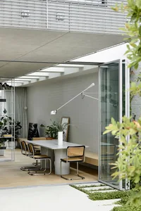 Modern minimalist dining room featuring sleek, contemporary furniture with a concrete table and wooden chairs.