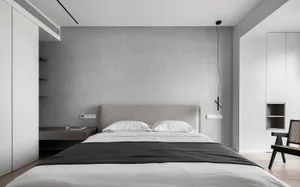 A minimalist bedroom featuring a grey concrete wall with a white bed and black accents.