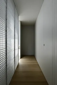 A minimalist interior space featuring wooden flooring and white walls and cabinets.