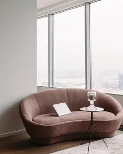 A minimalist living room featuring a soft, curved couch near a large window.