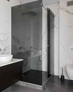A modern bathroom featuring marble walls and floor, a glass shower enclosure, and a floating vanity.